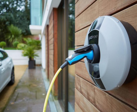 A blue and yellow electric car charger plugged into the wall.